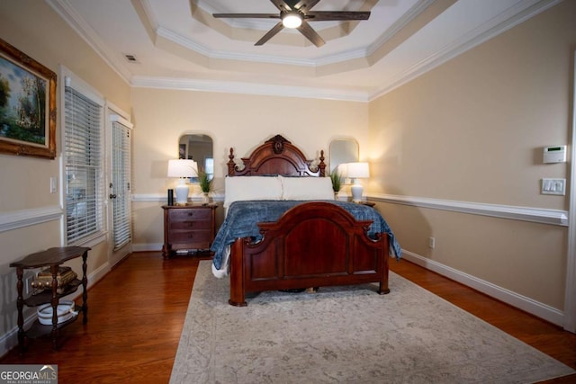 bedroom with a raised ceiling, crown molding, ceiling fan, and dark hardwood / wood-style flooring