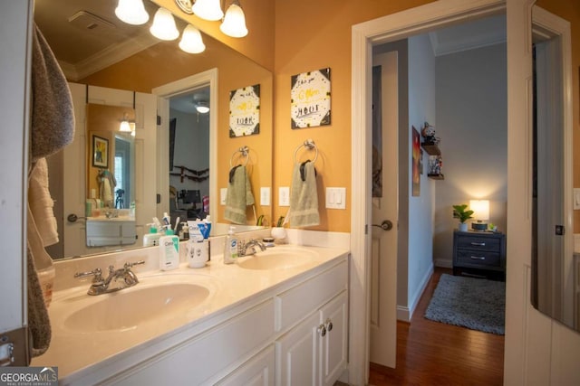 bathroom featuring hardwood / wood-style flooring, ornamental molding, vanity, and a chandelier