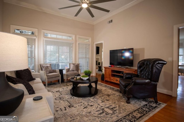 living room with dark hardwood / wood-style flooring, crown molding, and ceiling fan