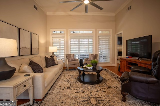 living room featuring ornamental molding, light wood-type flooring, and ceiling fan