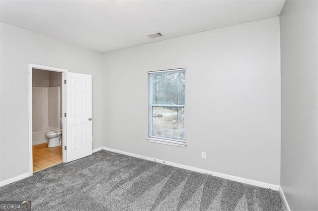 unfurnished bedroom featuring ensuite bathroom and carpet flooring