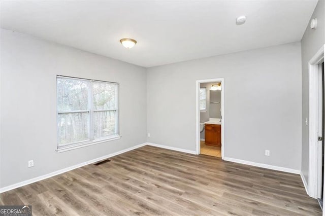 unfurnished bedroom featuring hardwood / wood-style flooring and ensuite bathroom