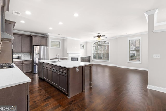 kitchen featuring sink, dark hardwood / wood-style flooring, stainless steel appliances, a kitchen island with sink, and decorative backsplash