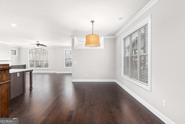 unfurnished living room featuring crown molding, plenty of natural light, and dark hardwood / wood-style flooring