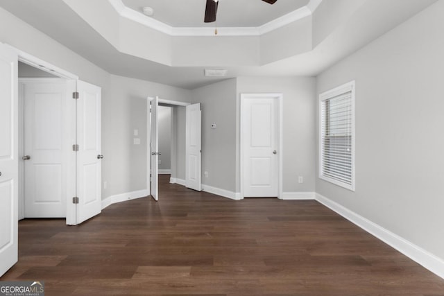 unfurnished bedroom featuring crown molding, dark hardwood / wood-style floors, ceiling fan, and a tray ceiling