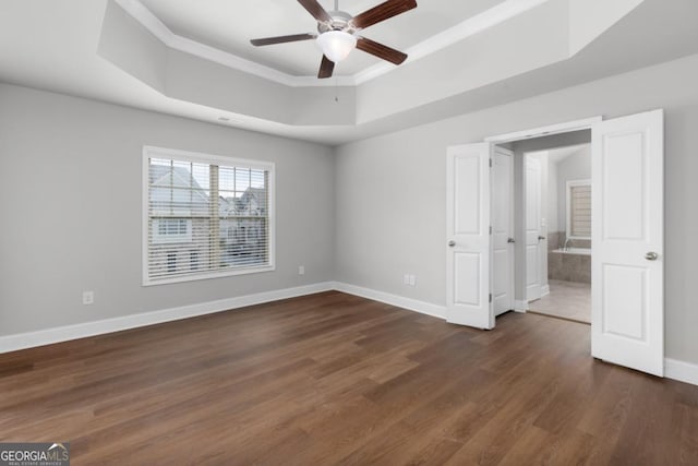 unfurnished bedroom with a tray ceiling, dark wood-type flooring, and ceiling fan