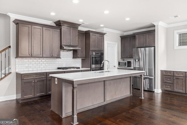 kitchen with dark brown cabinetry, dark wood-type flooring, stainless steel appliances, and a center island with sink