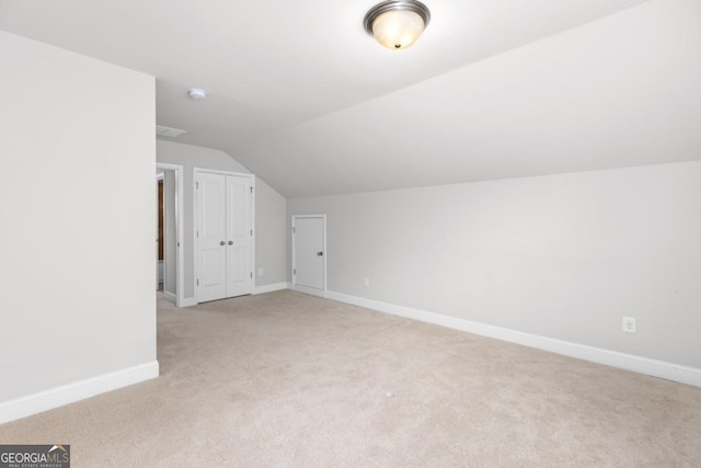 additional living space featuring vaulted ceiling and light carpet