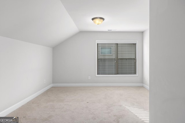 additional living space with lofted ceiling and light carpet