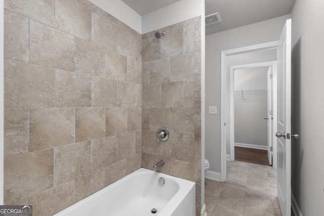 bathroom featuring tiled shower / bath and toilet