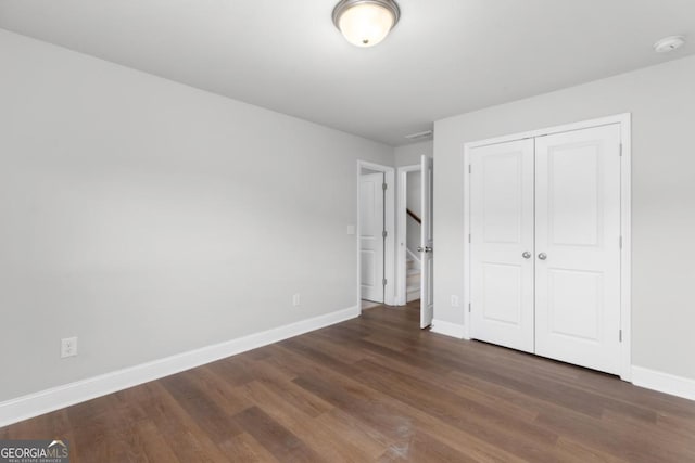 unfurnished bedroom with dark hardwood / wood-style floors and a closet