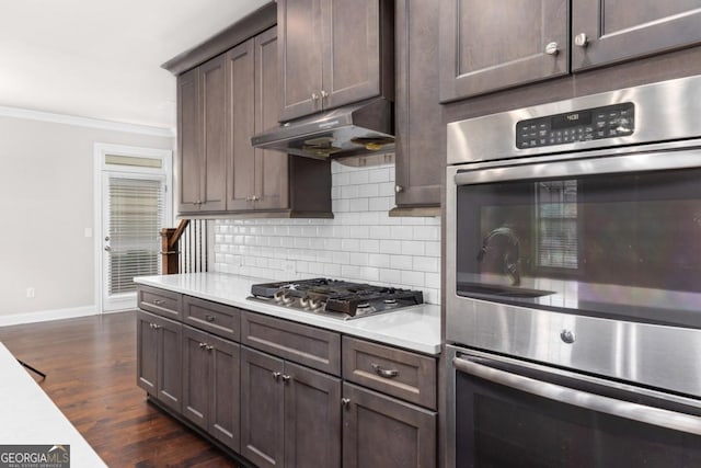 kitchen featuring tasteful backsplash, dark hardwood / wood-style flooring, dark brown cabinetry, stainless steel appliances, and crown molding