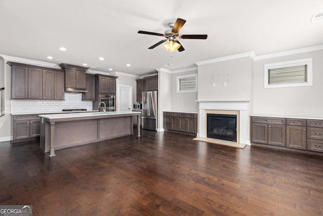 kitchen featuring dark brown cabinets, dark hardwood / wood-style floors, an island with sink, stainless steel appliances, and decorative backsplash