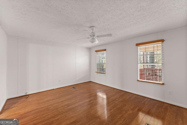 spare room with wood-type flooring, plenty of natural light, a textured ceiling, and ceiling fan