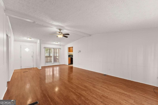 unfurnished living room with lofted ceiling with beams, ceiling fan, hardwood / wood-style floors, and a textured ceiling