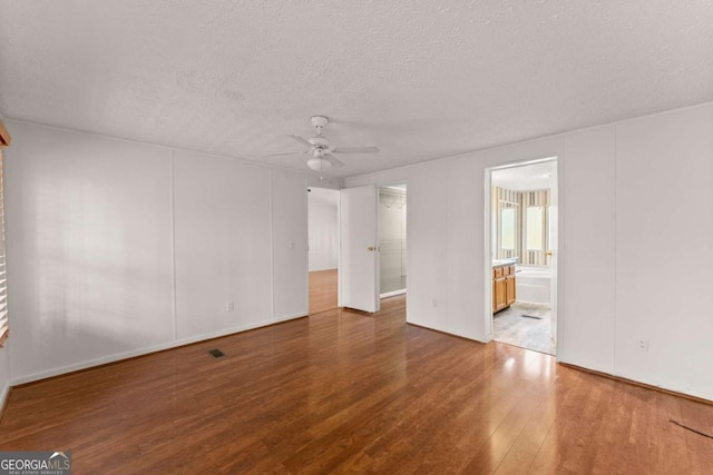 spare room featuring a textured ceiling, wood-type flooring, and ceiling fan