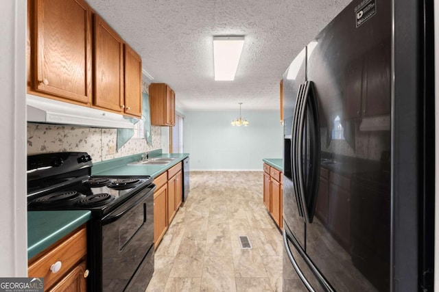 kitchen with sink, an inviting chandelier, hanging light fixtures, black appliances, and a textured ceiling