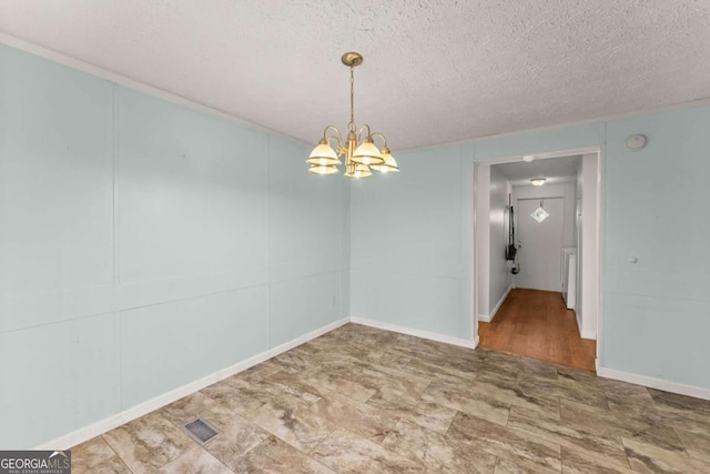 unfurnished room with a textured ceiling and a chandelier