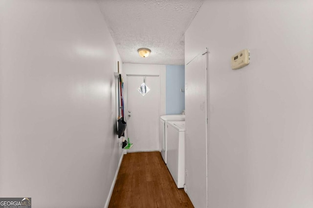 corridor with dark hardwood / wood-style flooring, washing machine and clothes dryer, and a textured ceiling