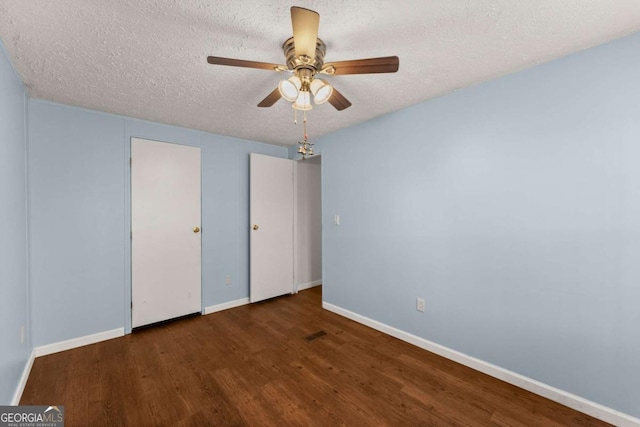 unfurnished bedroom with dark hardwood / wood-style flooring, ceiling fan, and a textured ceiling