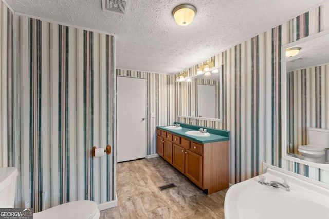 bathroom with vanity, a textured ceiling, and toilet