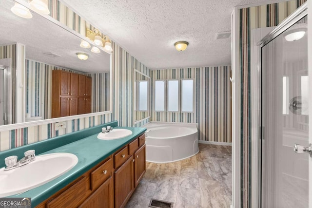 bathroom with plus walk in shower, vanity, and a textured ceiling