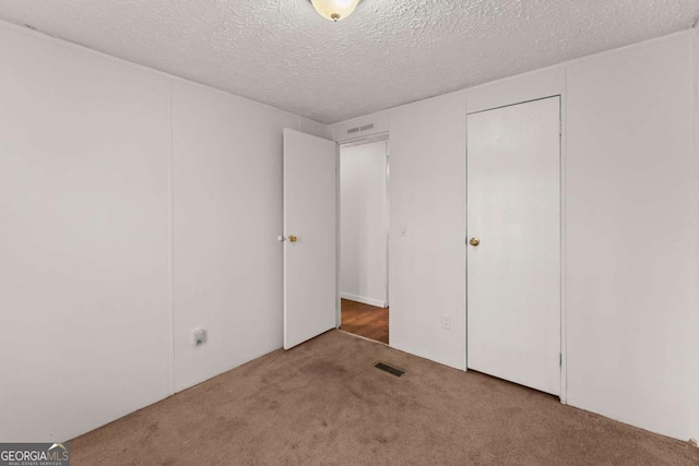 unfurnished bedroom featuring carpet, a textured ceiling, and a closet