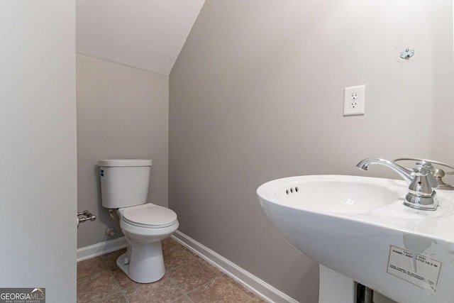 bathroom with lofted ceiling, sink, tile patterned floors, and toilet