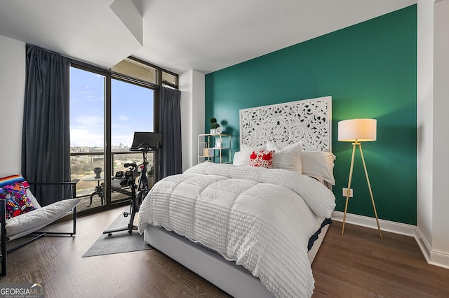 bedroom with expansive windows and dark wood-type flooring