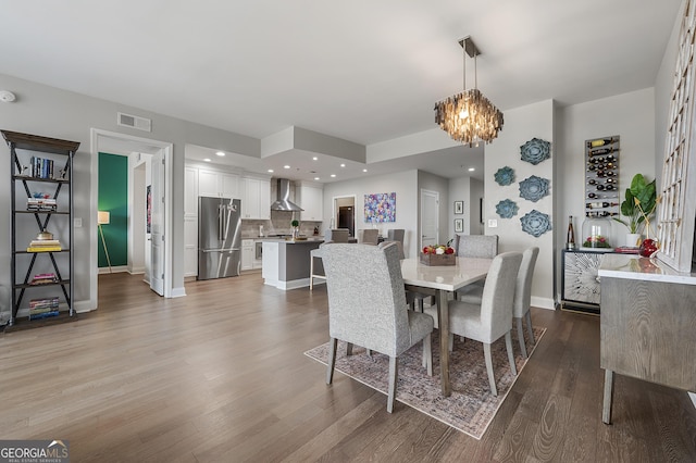 dining space featuring wood-type flooring and an inviting chandelier