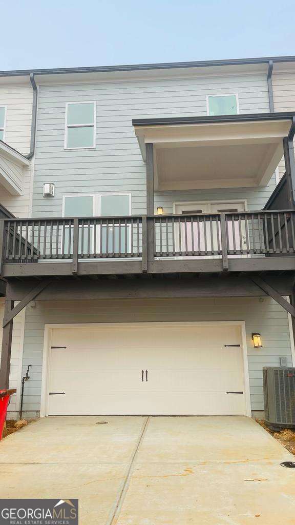 back of property featuring cooling unit, a garage, and a balcony