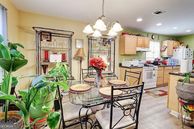 kitchen with a notable chandelier, light brown cabinetry, white appliances, and decorative light fixtures