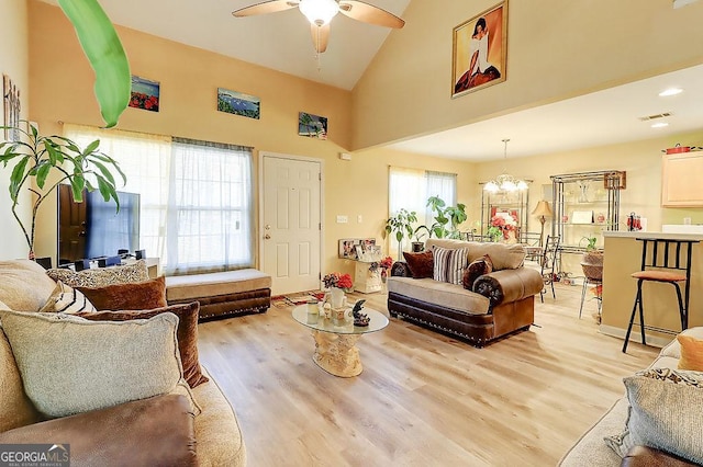 living room with high vaulted ceiling, ceiling fan with notable chandelier, and light hardwood / wood-style flooring