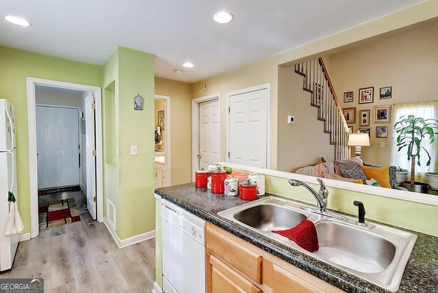 kitchen featuring sink, white appliances, light hardwood / wood-style flooring, and light brown cabinets