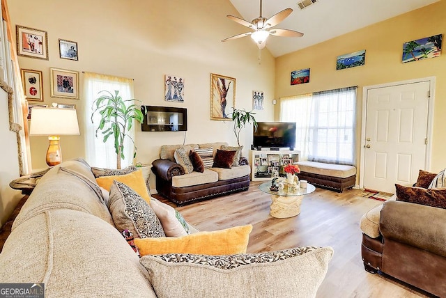 living room featuring ceiling fan, high vaulted ceiling, and light wood-type flooring