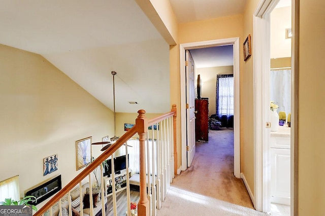 hallway featuring vaulted ceiling and light carpet