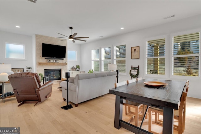 living room with ceiling fan, a fireplace, light hardwood / wood-style floors, and a healthy amount of sunlight