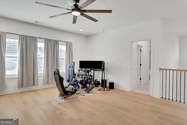 exercise area with ceiling fan and light hardwood / wood-style floors