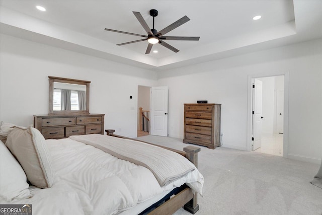 bedroom with ceiling fan, a tray ceiling, and light carpet