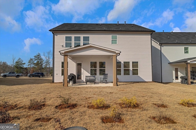 rear view of house featuring a lawn and a patio