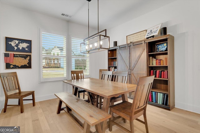 dining room with a barn door and light hardwood / wood-style floors