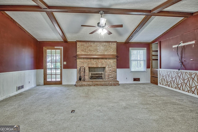 unfurnished living room with a brick fireplace, lofted ceiling with beams, a textured ceiling, and carpet