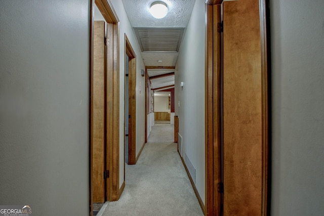 hall featuring light colored carpet and a textured ceiling