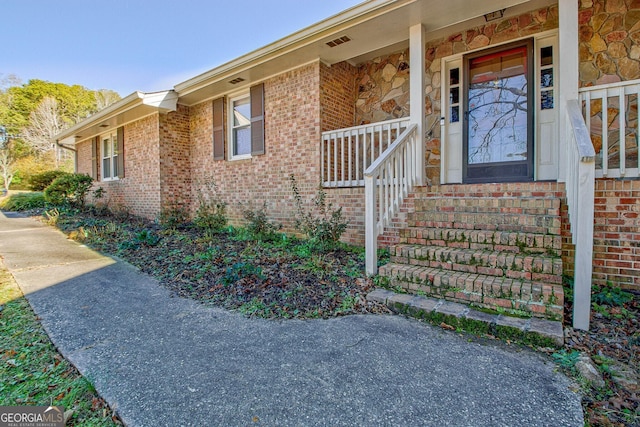 property entrance with covered porch and brick siding