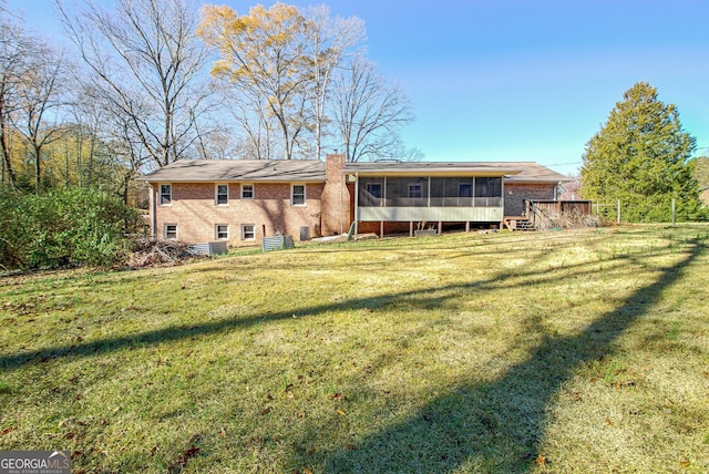 rear view of house featuring a sunroom and a lawn