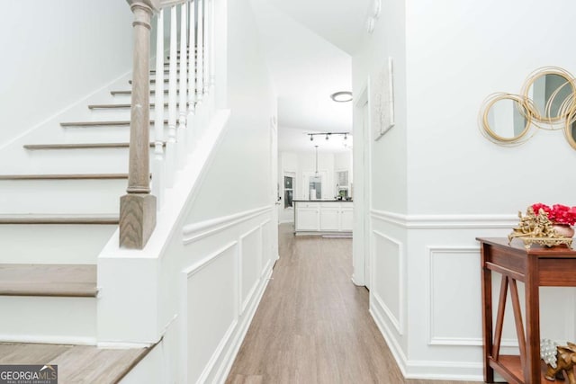 stairs with track lighting and wood-type flooring