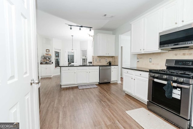 kitchen featuring pendant lighting, tasteful backsplash, white cabinetry, light hardwood / wood-style floors, and stainless steel appliances