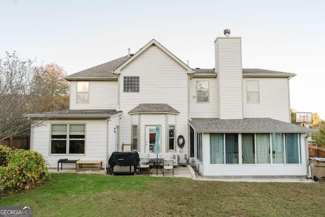 back of house featuring a patio area, a sunroom, outdoor lounge area, and a lawn