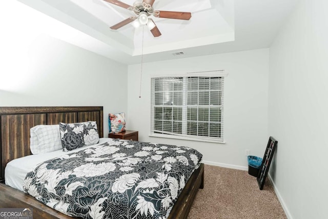 bedroom with carpet floors, a raised ceiling, and ceiling fan