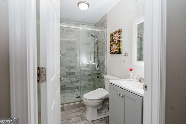 bathroom featuring vanity, an enclosed shower, and toilet